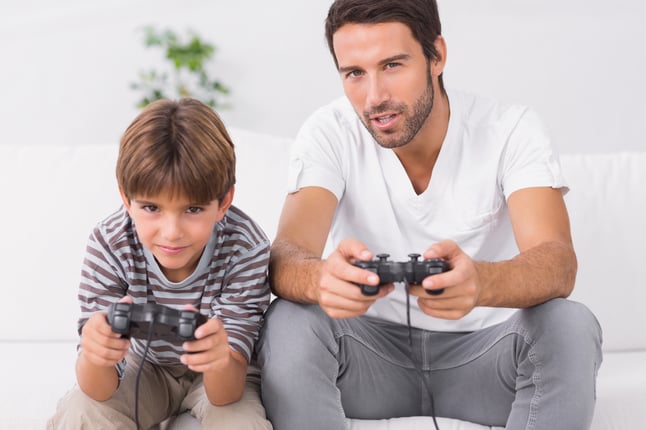 Father and son playing video games on the couch